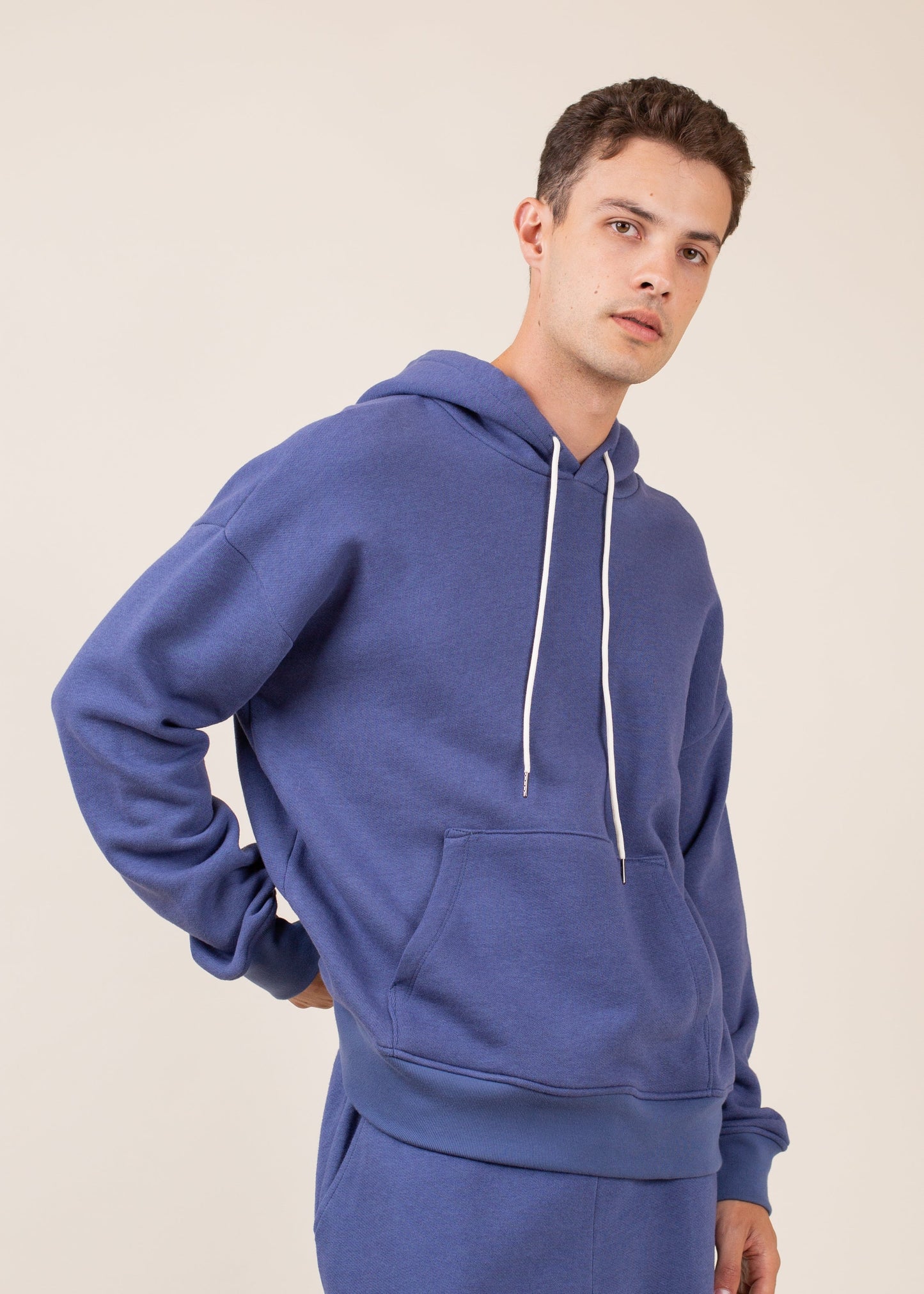 Man wearing a blue hoodie and matching sweatpants, minimalist background, men's fashion