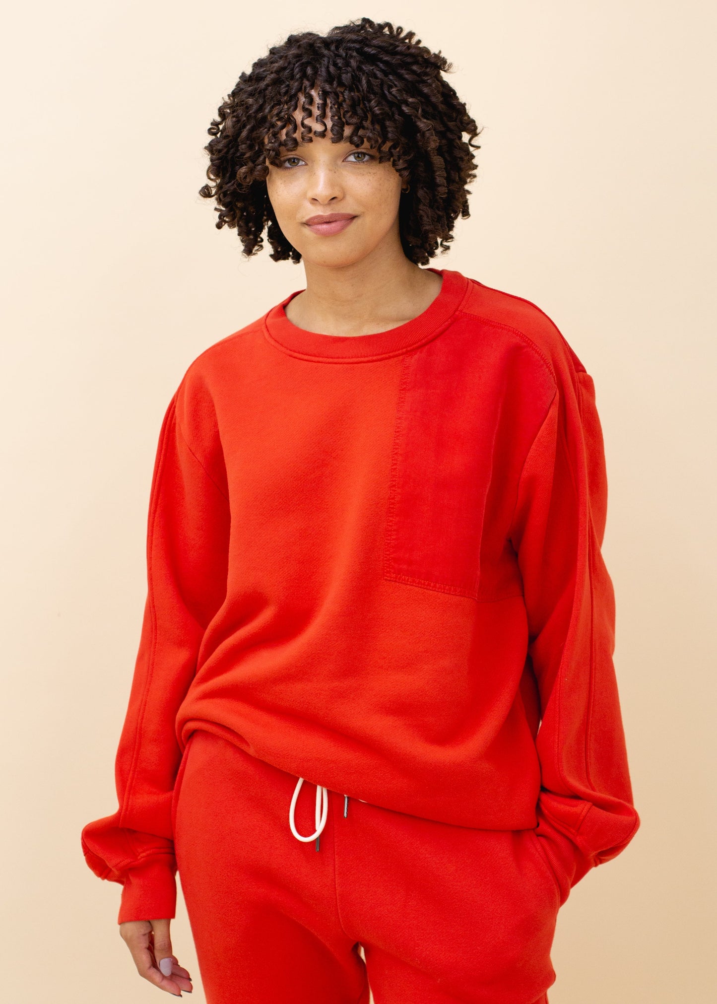 Person wearing a red sweatshirt and sweatpants, showcasing casual MANN fashion style