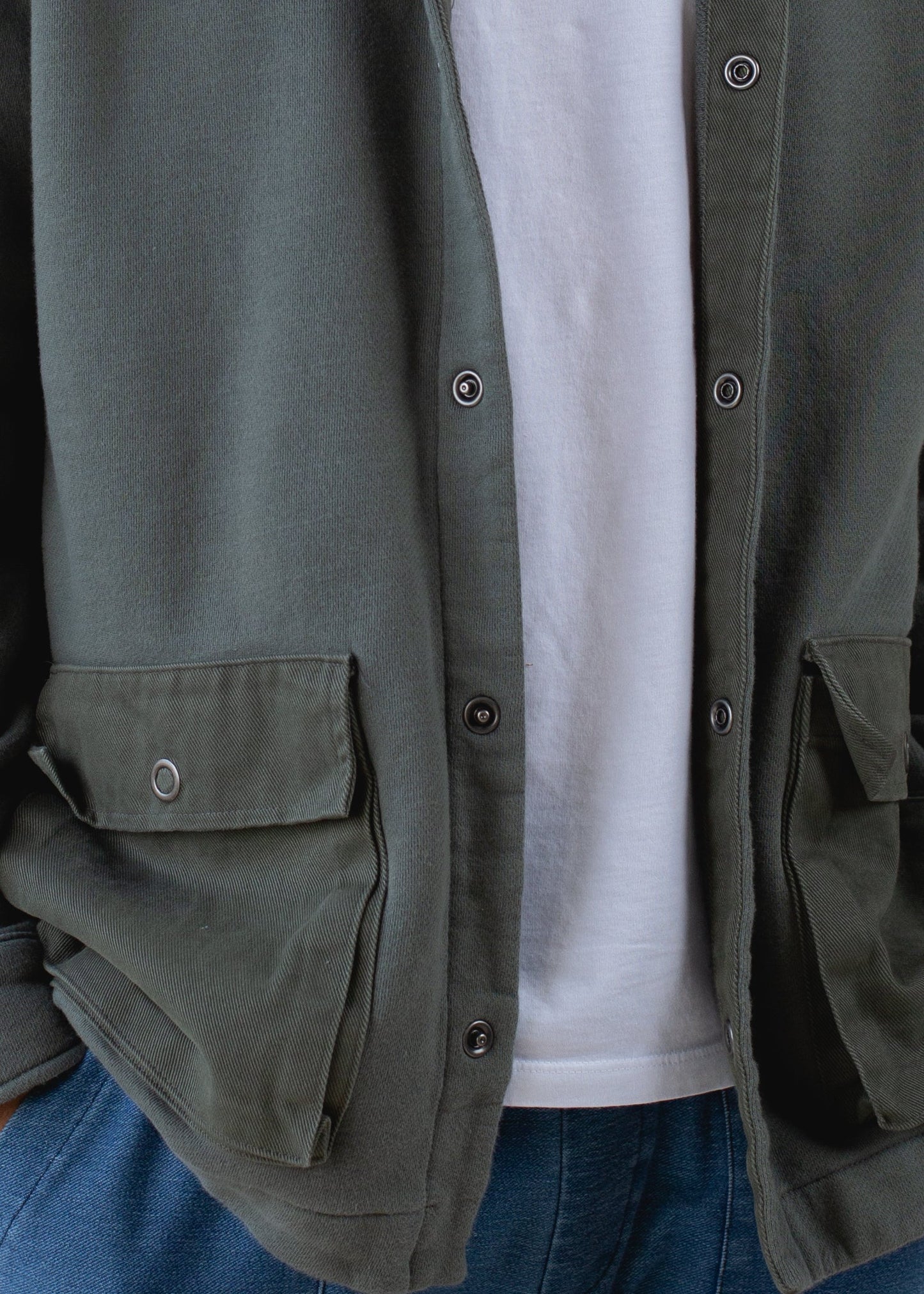 Men's green utility jacket with snap buttons and front pockets, styled over white shirt