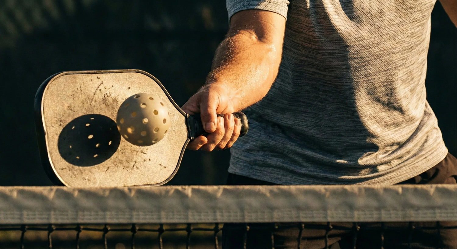 Man playing pickleball with paddle and perforated ball near net, athletic lifestyle