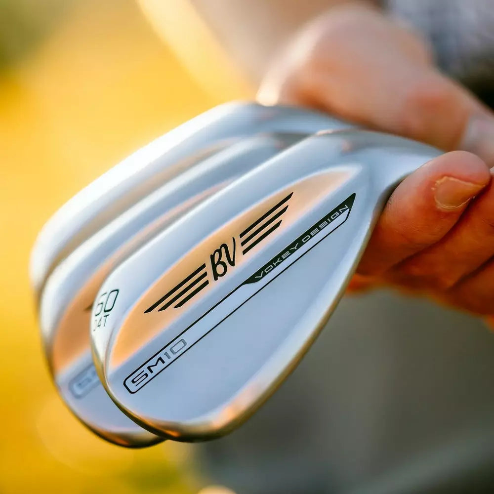 Close-up of hand holding Titleist Vokey Design golf wedges, SM10, outdoors