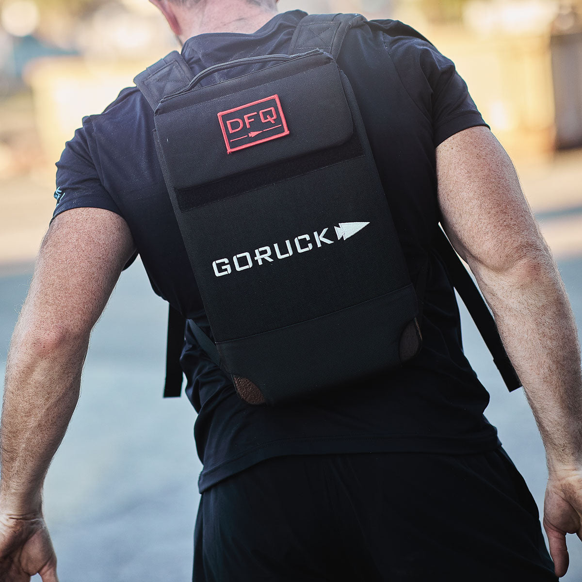 Man wearing black GORUCK backpack outdoors, curated men's gear, MANN marketplace style.