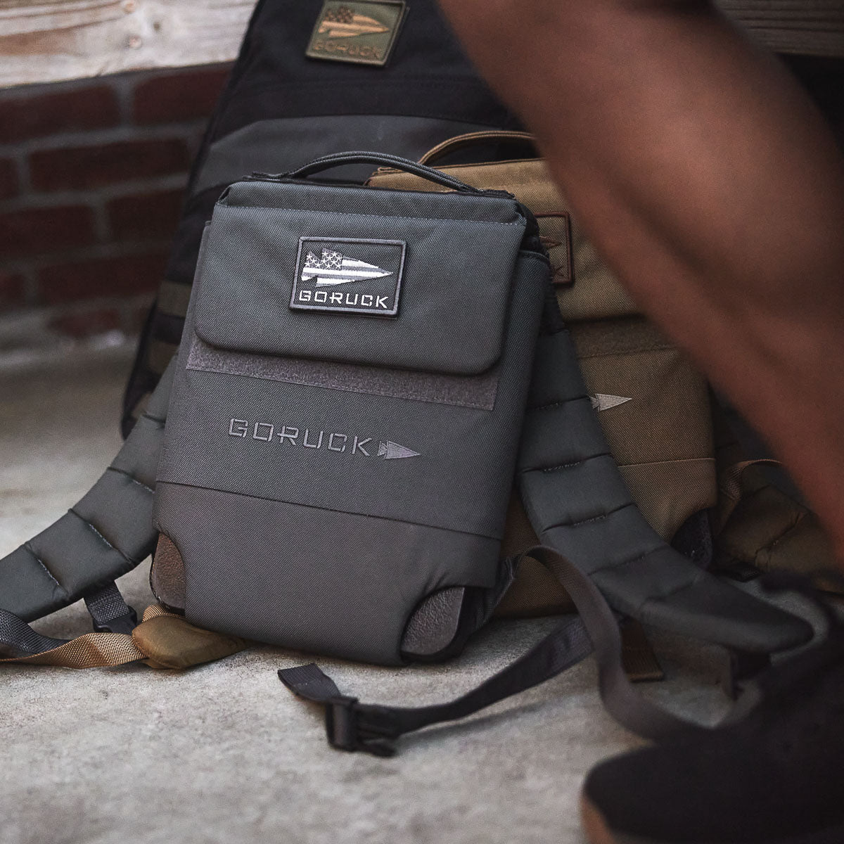 GORUCK men’s tactical backpack with patch, placed outdoors on concrete near brick wall