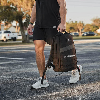 Man in athletic wear carrying a GORUCK backpack outdoors, curated men's lifestyle gear