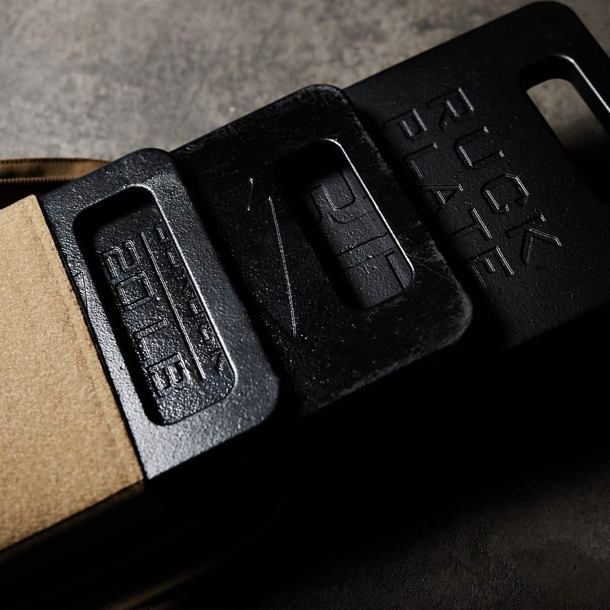 Close-up of black ruck plates with embossed text for men's fitness gear on Mann marketplace
