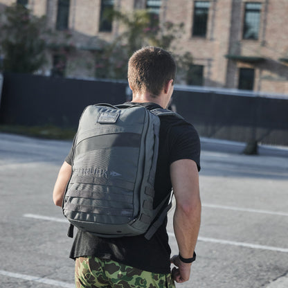 Man wearing GORUCK backpack and camo shorts outdoors, modern men’s gear lifestyle