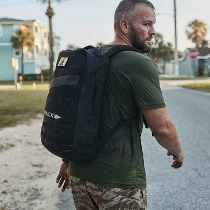 Man in olive shirt with black backpack on street, masculine outdoor lifestyle gear