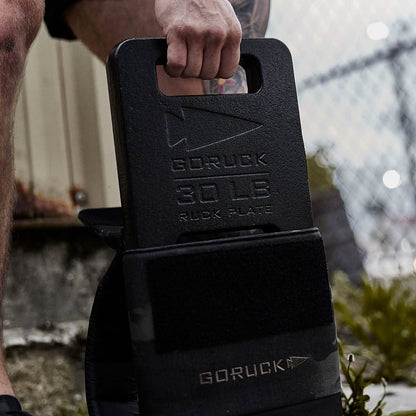 Man holding a 30 LB GORUCK ruck plate outdoors, perfect for men's fitness and training gear