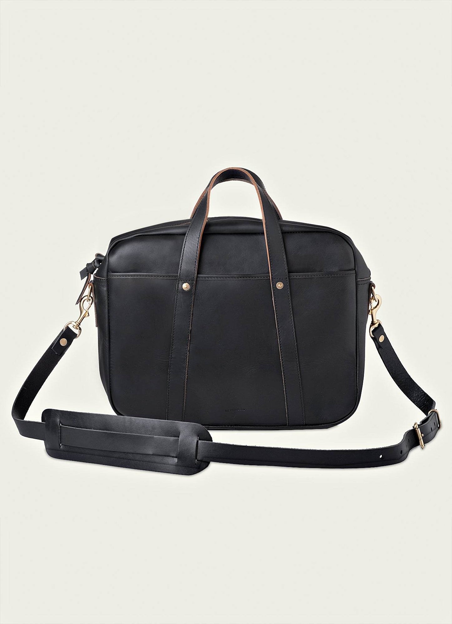 Men’s black leather briefcase with top handles and adjustable shoulder strap on light background