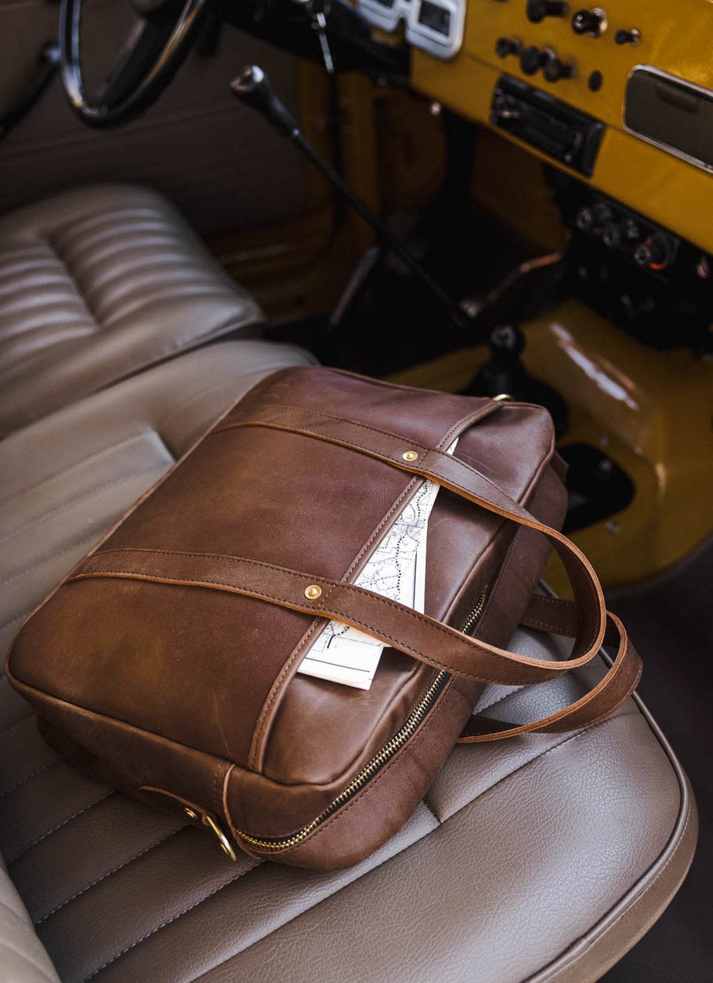 Brown leather men's briefcase with map on car seat, MANN lifestyle accessory