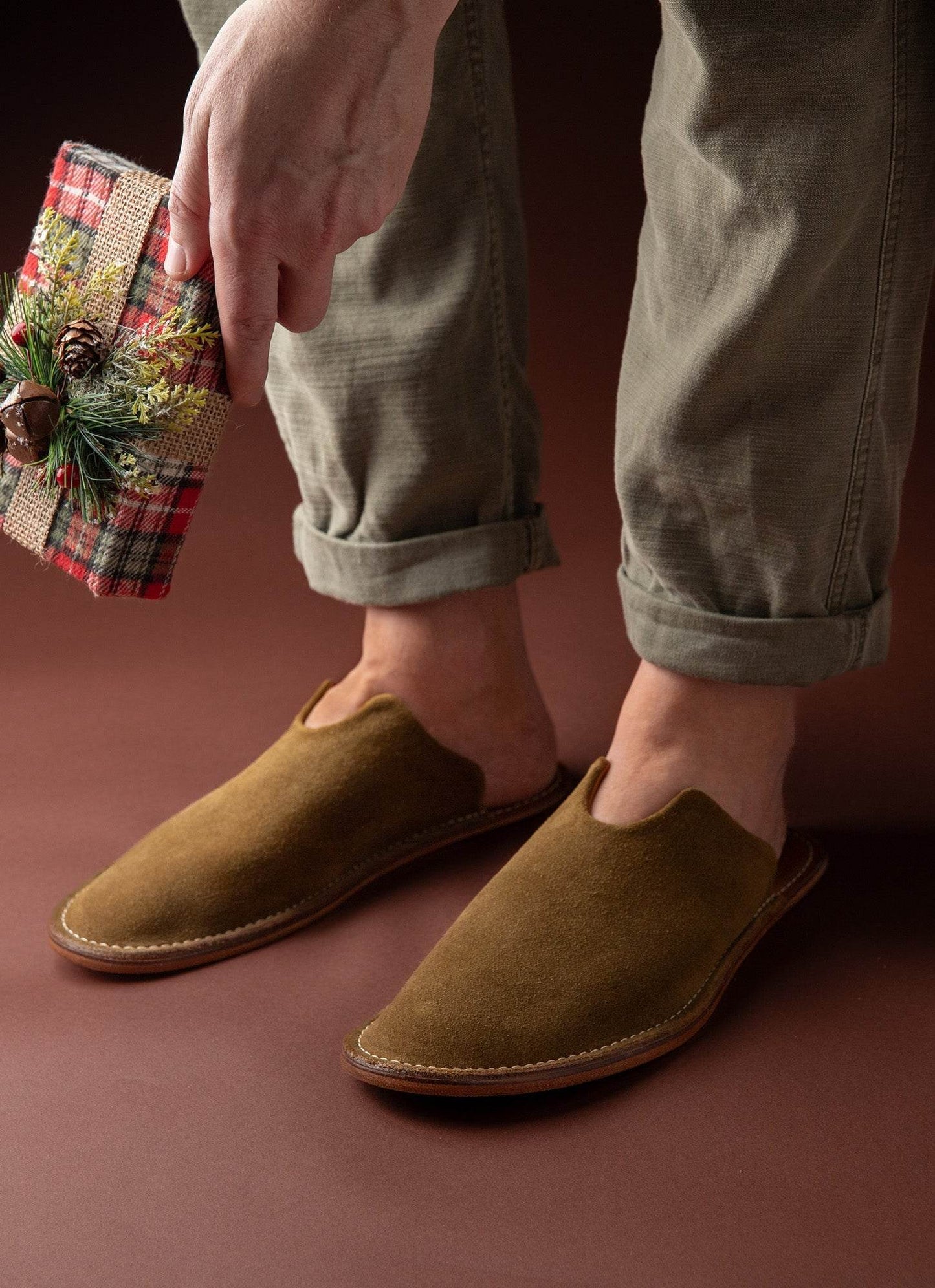 Men's brown suede slippers and rolled khaki pants with a festive gift, lifestyle fashion