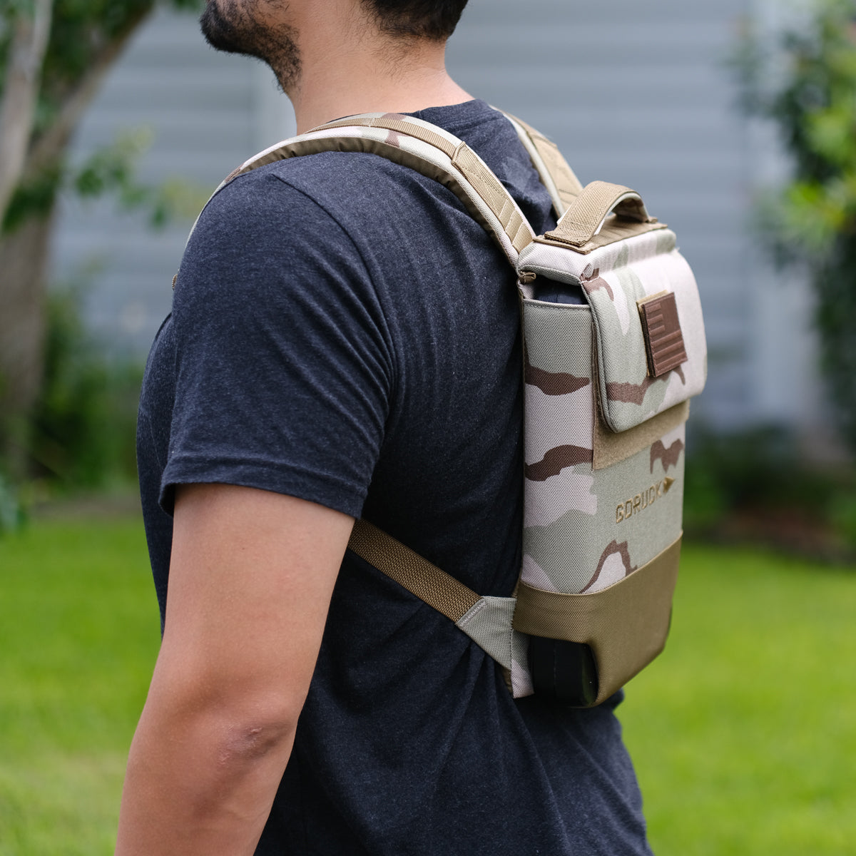 Man outdoors wearing camo backpack, GORUCK bag featured, casual black t-shirt style