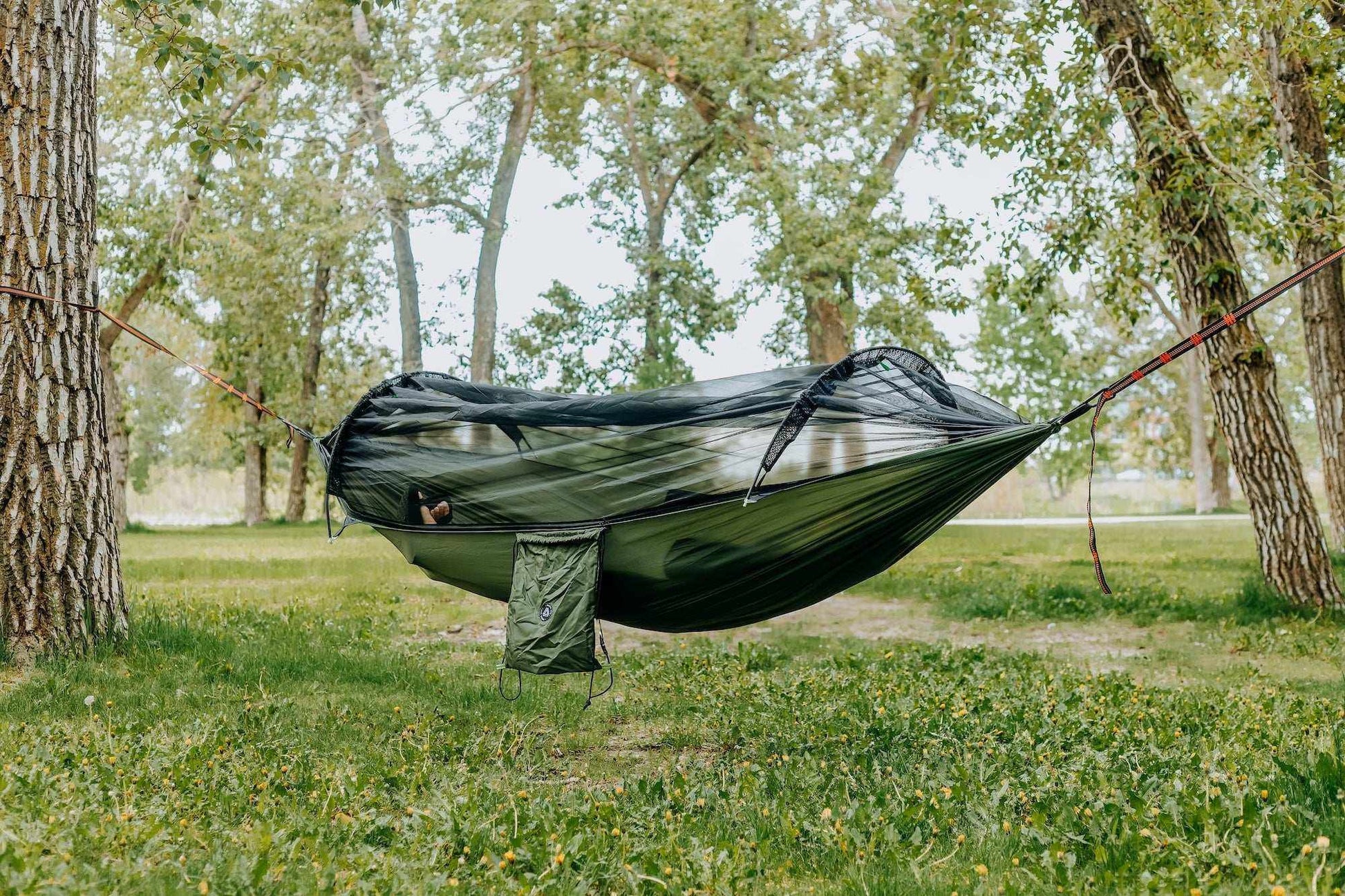Lightweight hammock with mosquito net in a forest setting for outdoor comfort.