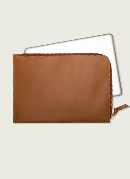 Tan leather laptop sleeve case with zipper, minimalist men's tech accessory on neutral background