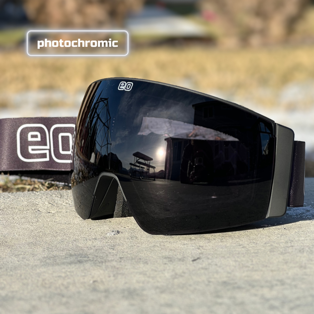 Black photochromic ski goggles with reflective lens and EQ logo, outdoor setting, men's gear