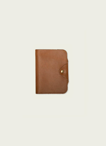 Tan leather passport wallet for men with snap closure, minimalist design on white background