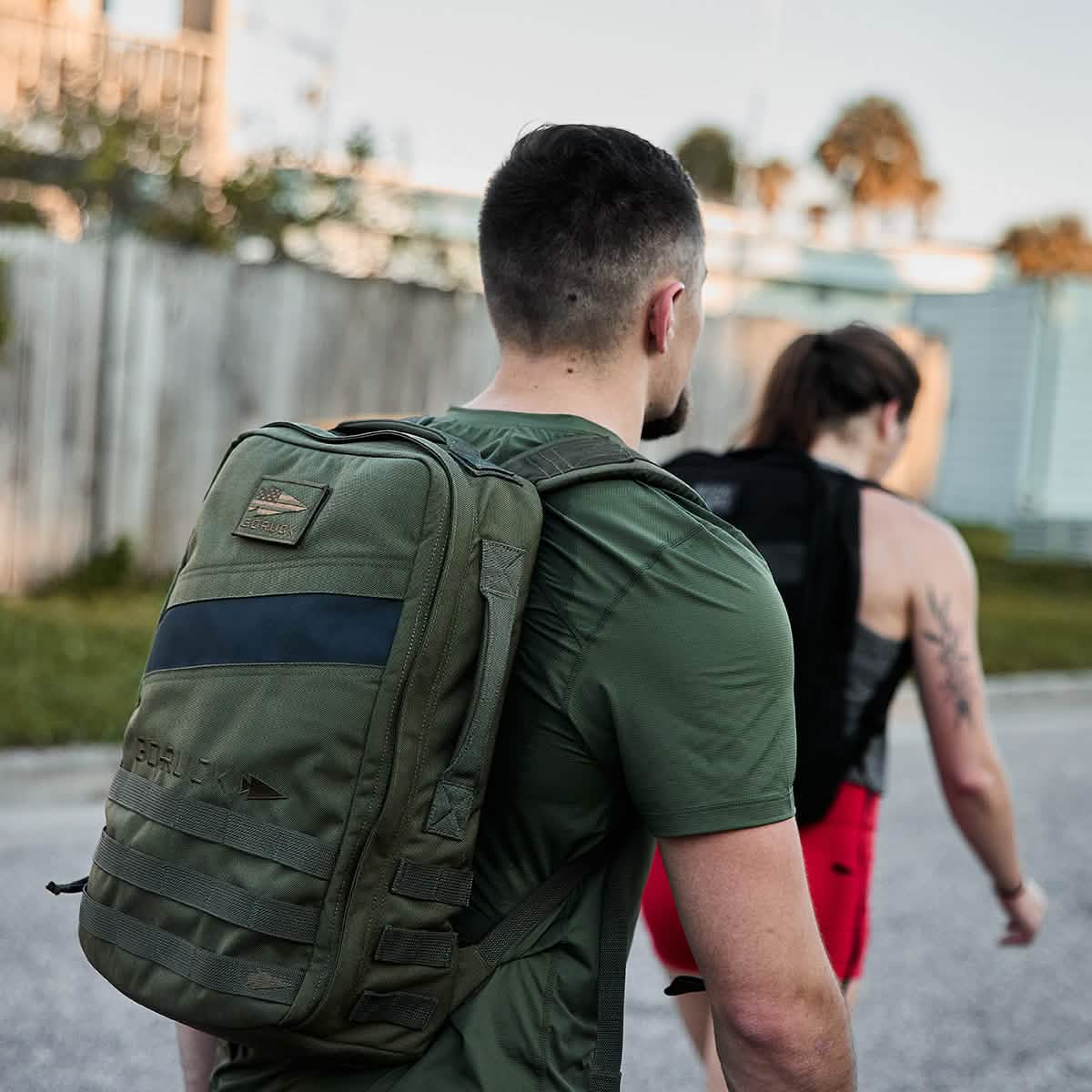 Man wearing a green tactical backpack walking outdoors, active lifestyle gear for men