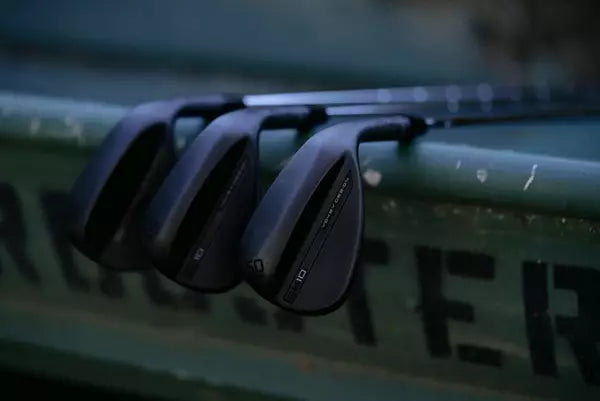Set of black golf clubs leaning on a green surface, ideal for men's lifestyle and grooming market