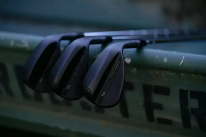 Set of black golf clubs leaning on a green surface, ideal for men's lifestyle and grooming market