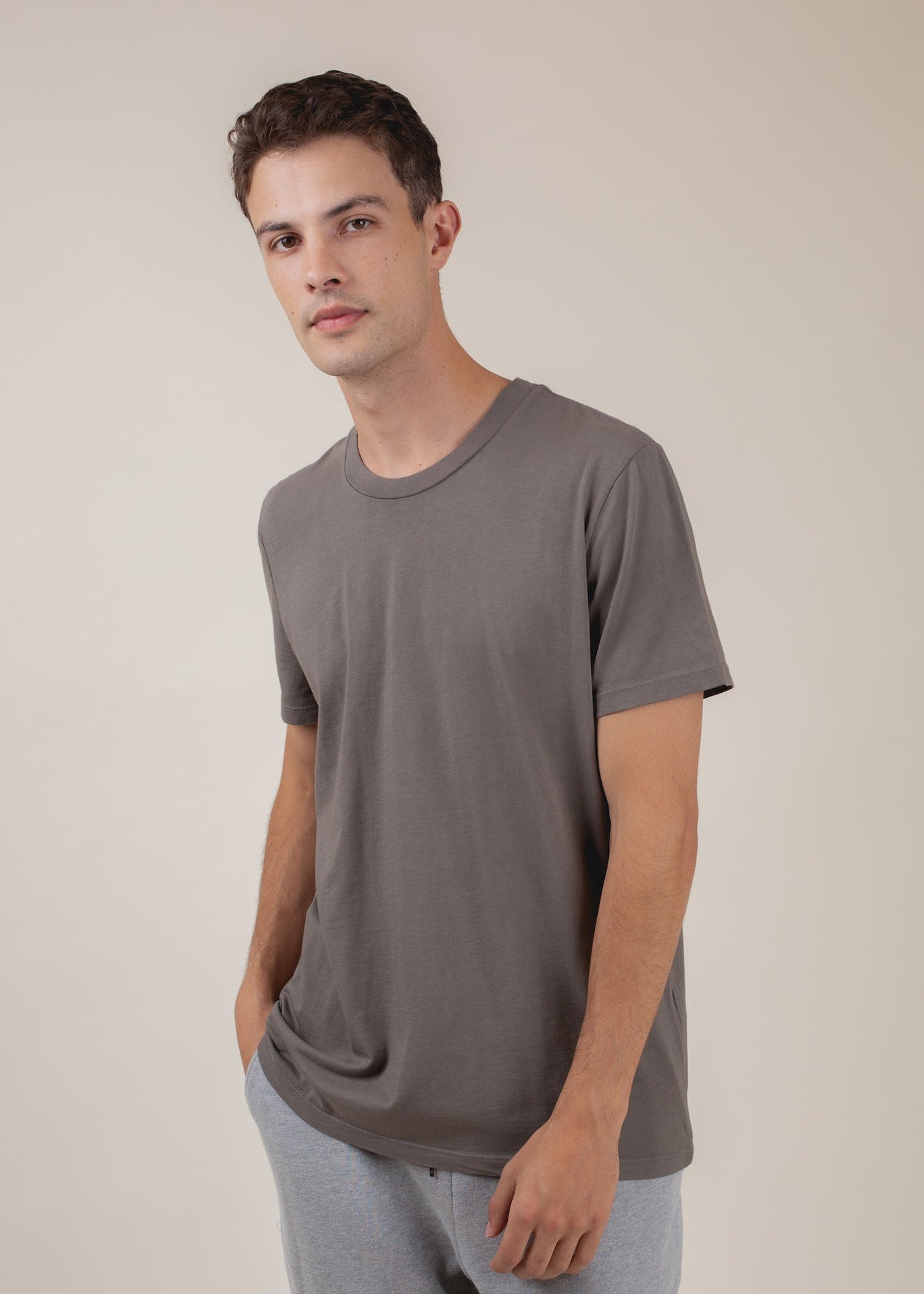Man modeling a cement gray basic tee, casual men's fashion on neutral background