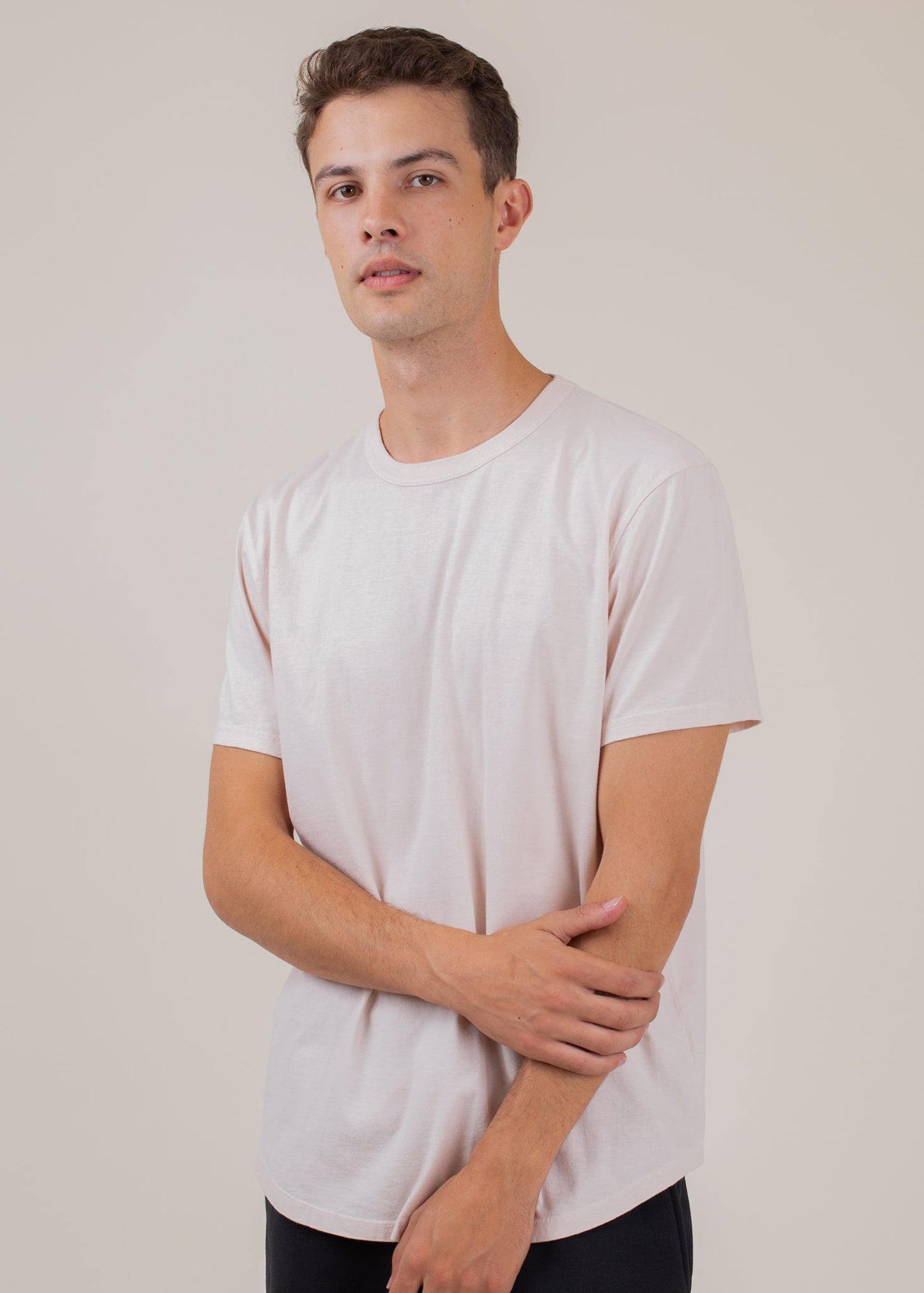 Man wearing a light pink classic tee, short sleeves, on a plain background for MANN fashion.