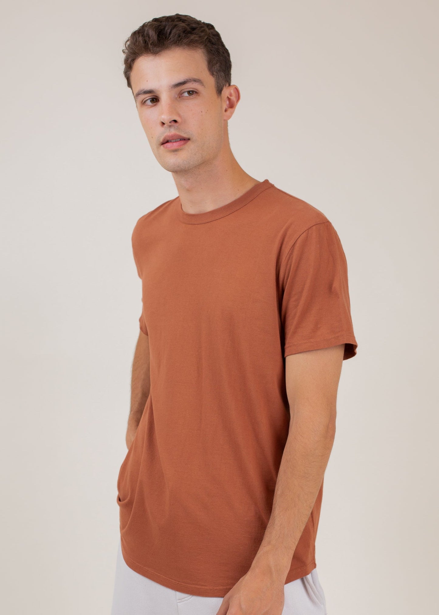 Man wearing rust classic tee, minimalist men's fashion, neutral background, MANN marketplace
