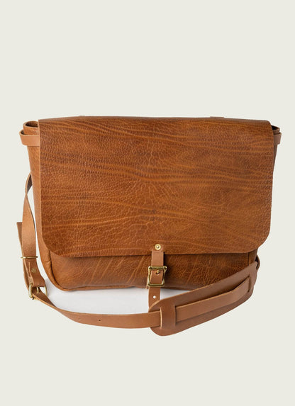 Men’s tan leather messenger bag with adjustable strap and brass buckle, ideal for work or travel