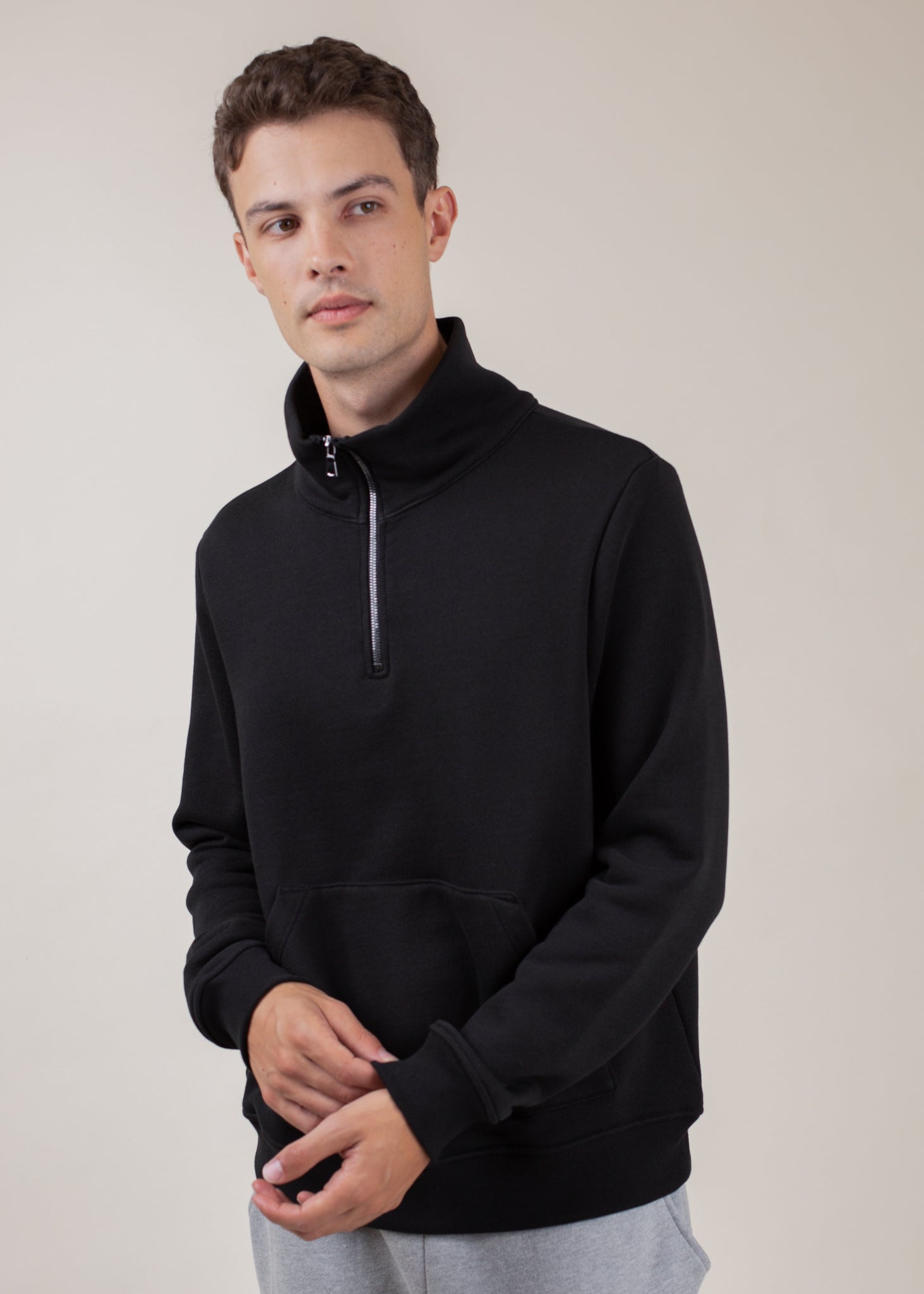 Man wears black half-zip sweatshirt with kangaroo pocket, modern men's fashion from MANN