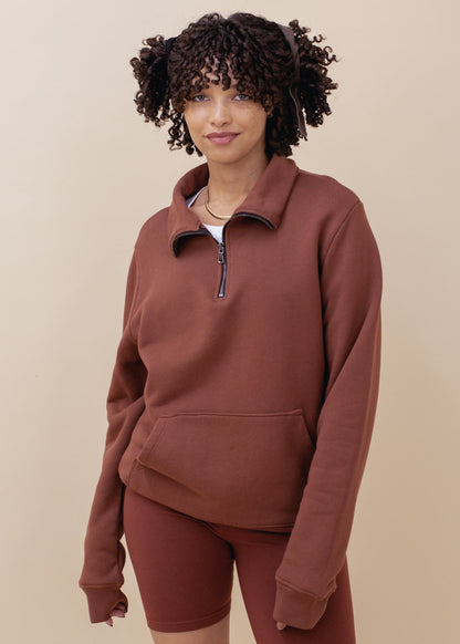 Woman wearing a brick half-zip sweatshirt and matching shorts, neutral background, MANN fashion