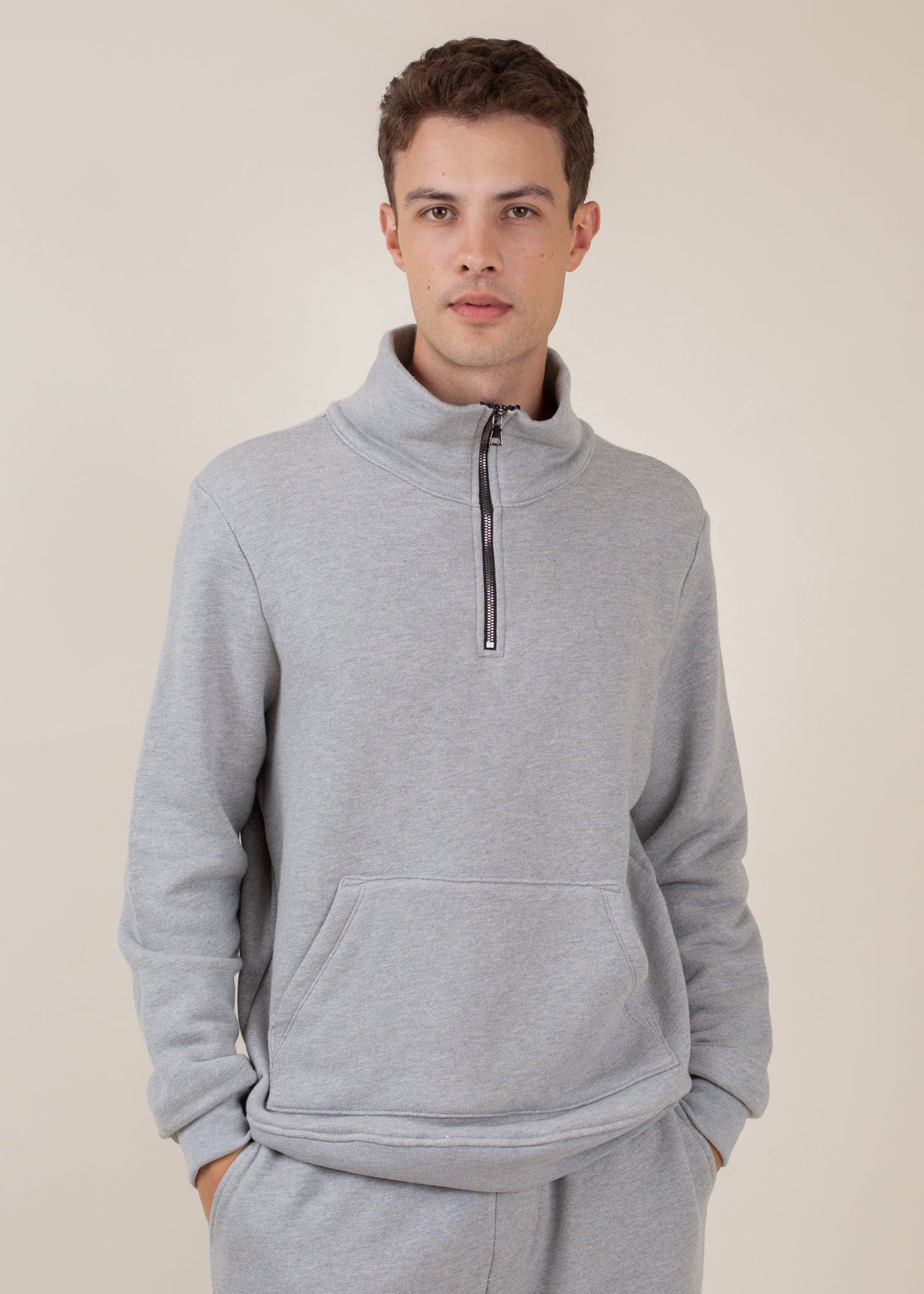 Man wearing a light grey half-zip sweatshirt with kangaroo pocket, casual menswear style