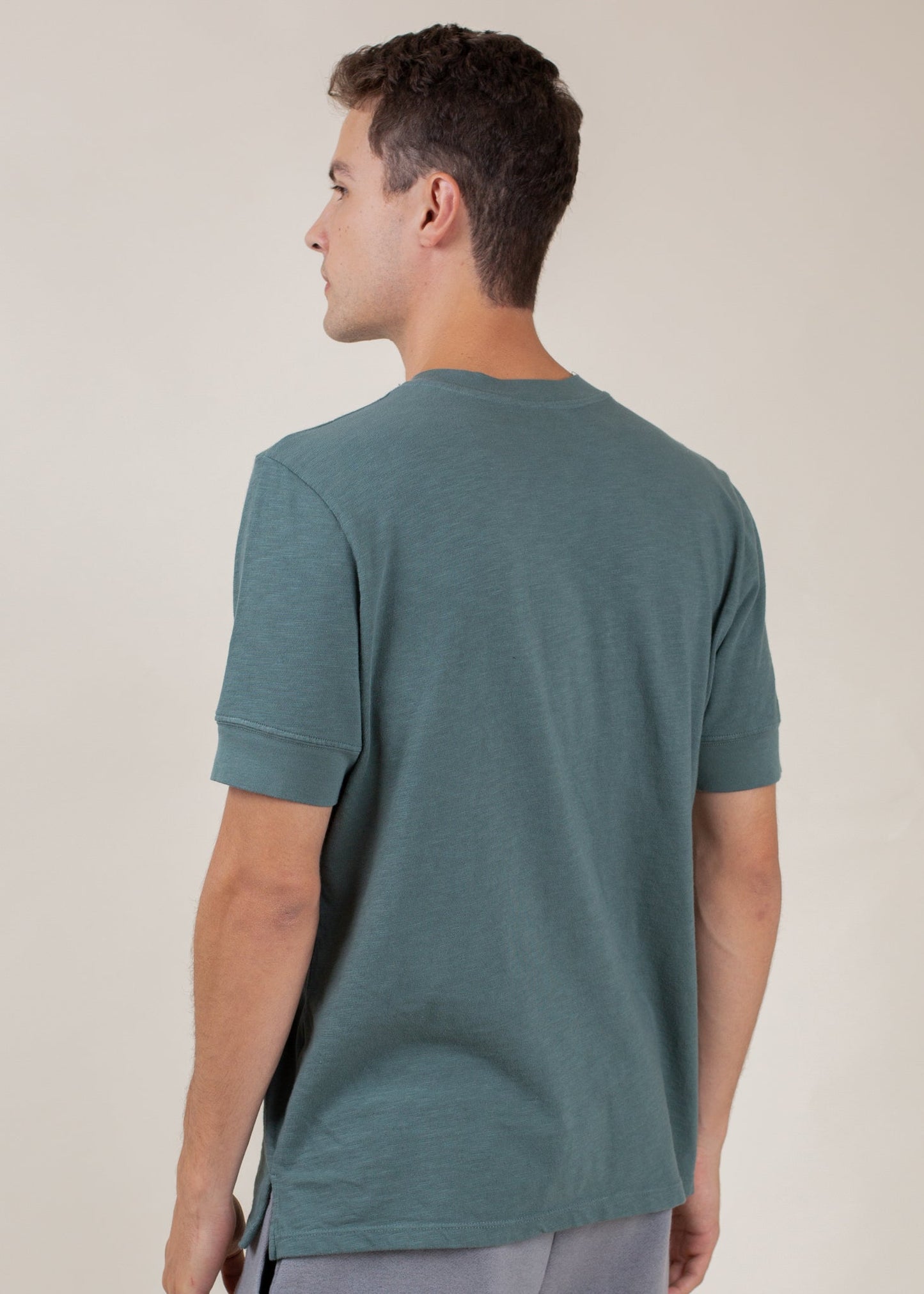 Man wearing pine green short-sleeve Henley tee, back view, casual menswear by MANN
