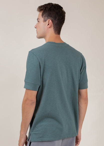 Man wearing pine green short-sleeve Henley tee, back view, casual menswear by MANN