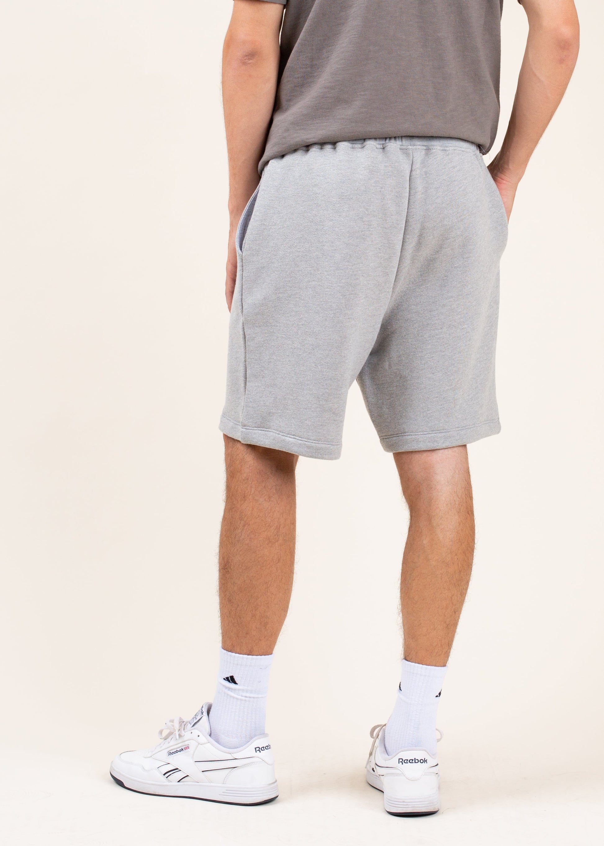 Man wearing gray athletic shorts, white socks, and white sneakers, casual mens fashion