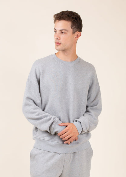 Man modeling gray crewneck sweatshirt and sweatpants, men's fashion on neutral background