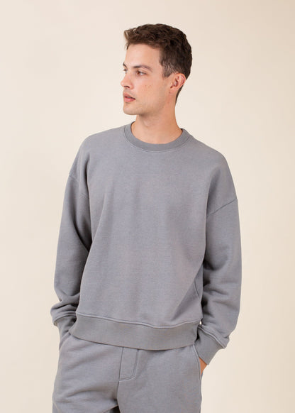 Man wearing a grey crewneck sweatshirt and sweatpants, casual menswear for MANN marketplace