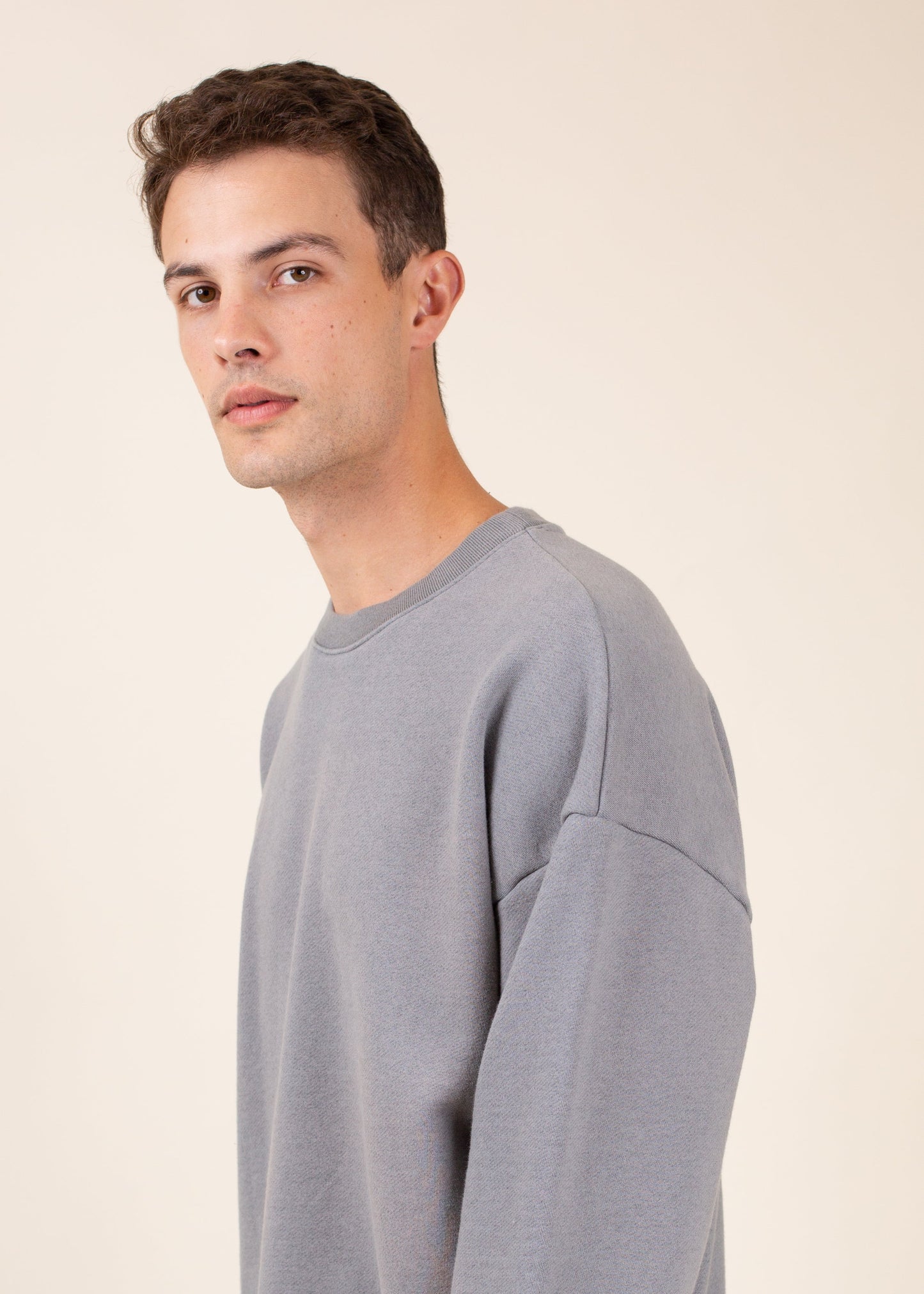 Man in a minimalist grey sweatshirt, neutral background, modern men's fashion style