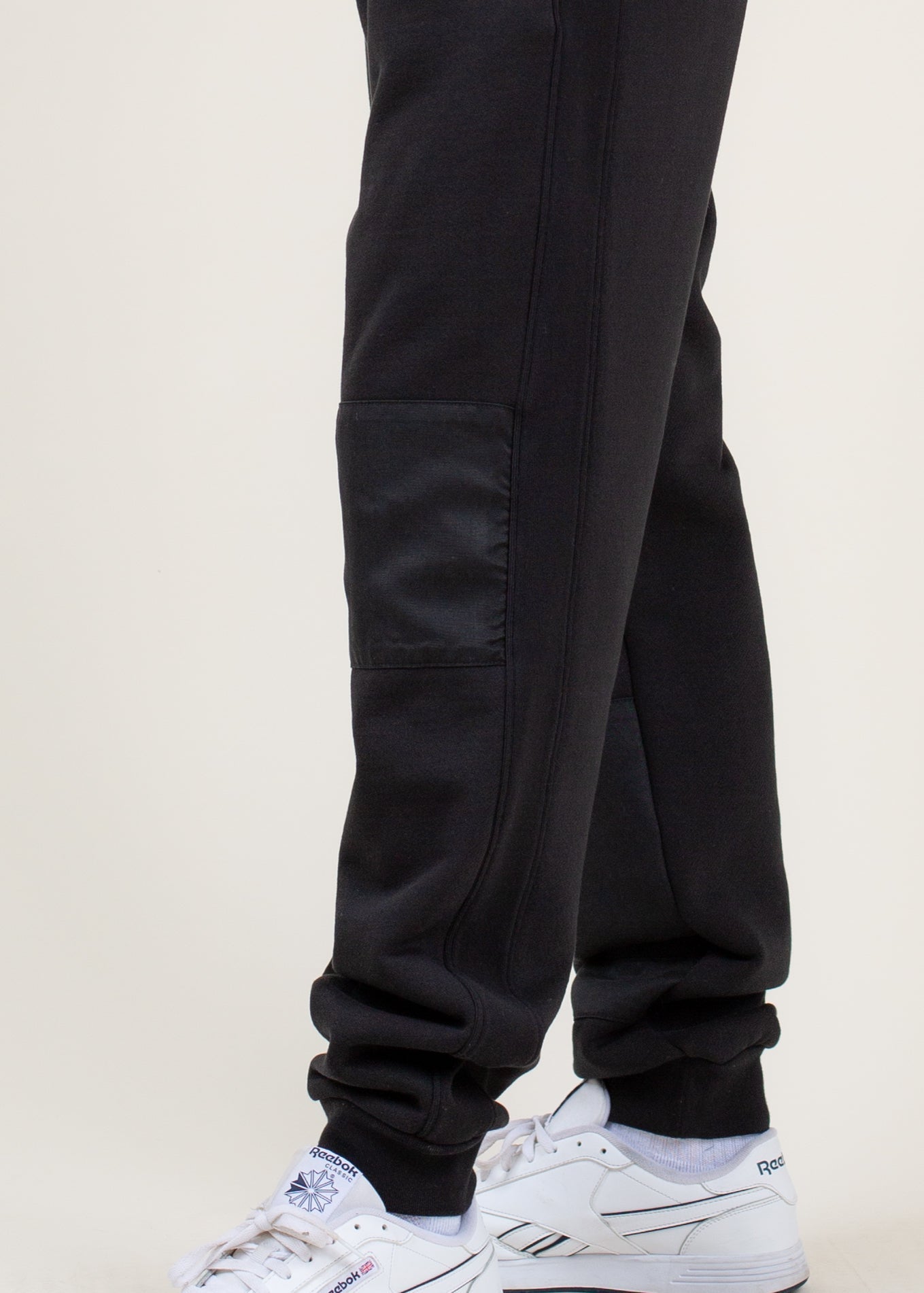 Men's black jogger pants with side pocket, styled with white Reebok sneakers, MANN fashion