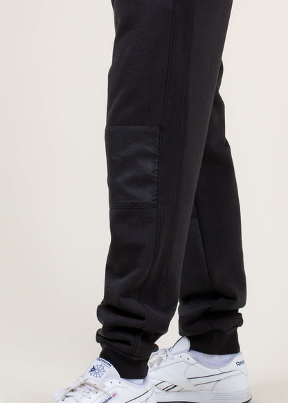 Men's black jogger pants with side pocket, styled with white Reebok sneakers, MANN fashion