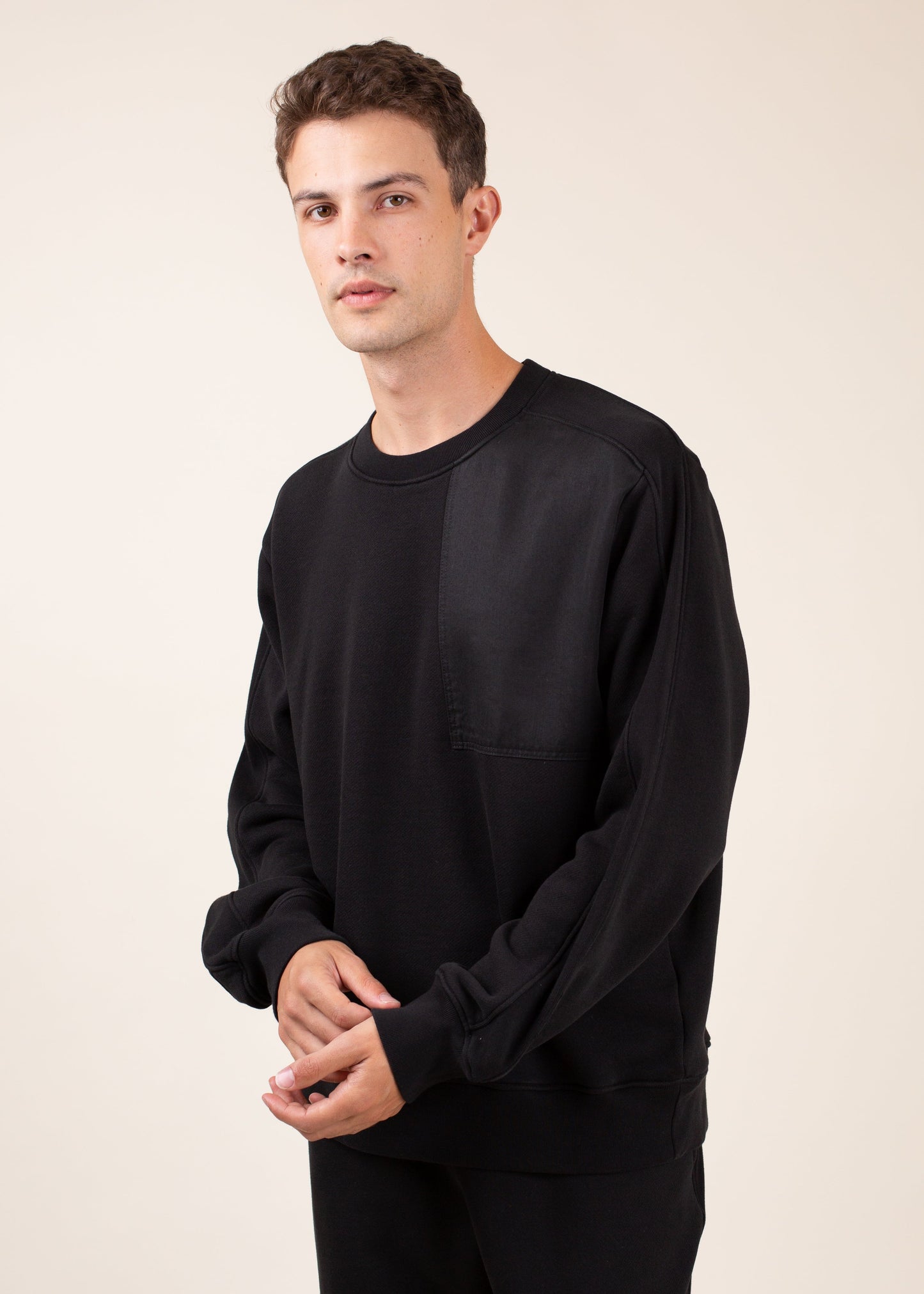 Man wearing a black crewneck sweatshirt with chest pocket, stylish men's fashion on MANN