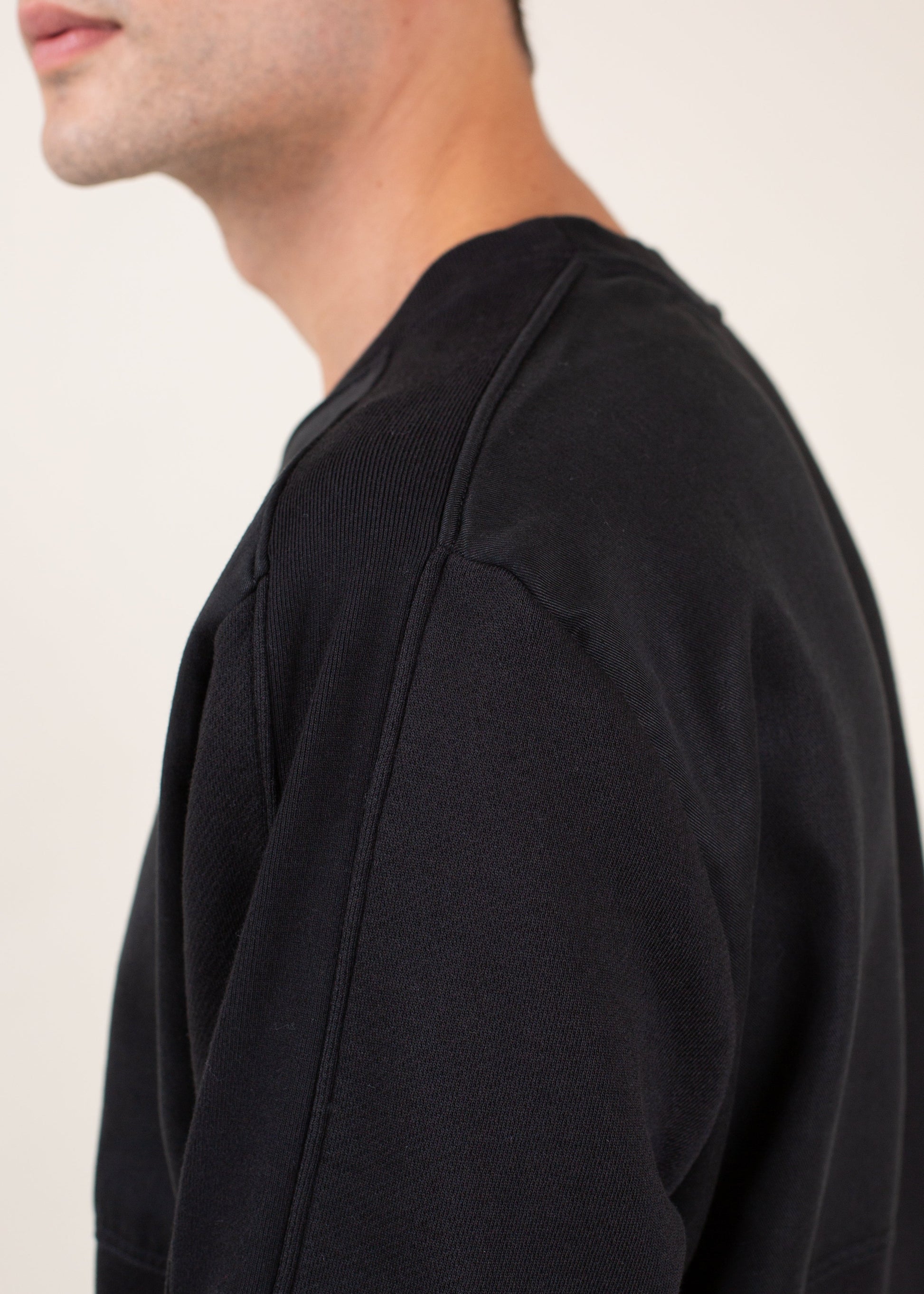 Close-up of a man wearing a black crewneck sweatshirt, minimalist menswear fashion