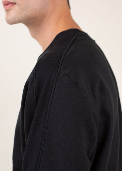 Close-up of a man wearing a black crewneck sweatshirt, minimalist menswear fashion