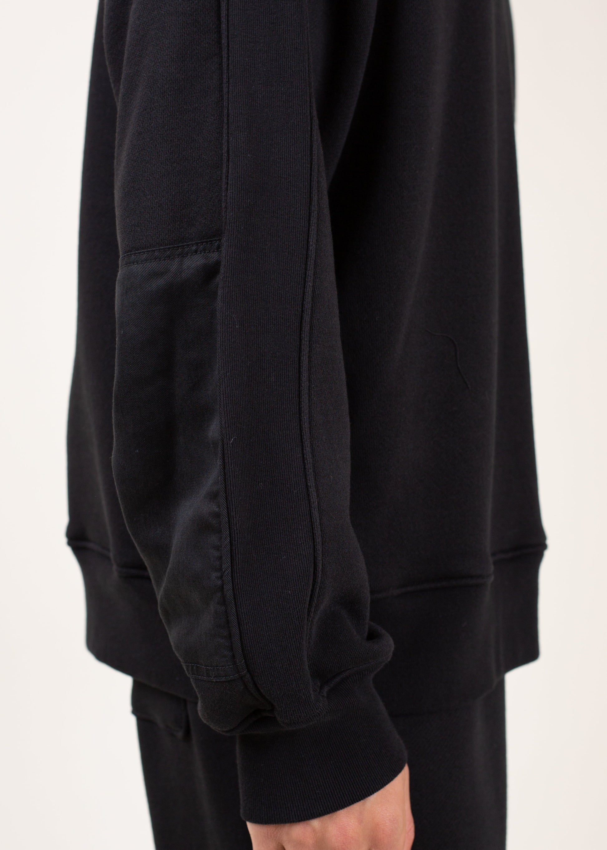Closeup of a man’s black sweatshirt with unique sleeve detail, casual men’s fashion on MANN