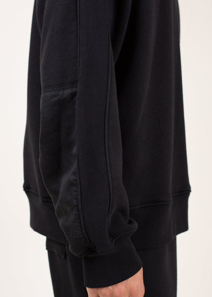 Closeup of a man’s black sweatshirt with unique sleeve detail, casual men’s fashion on MANN