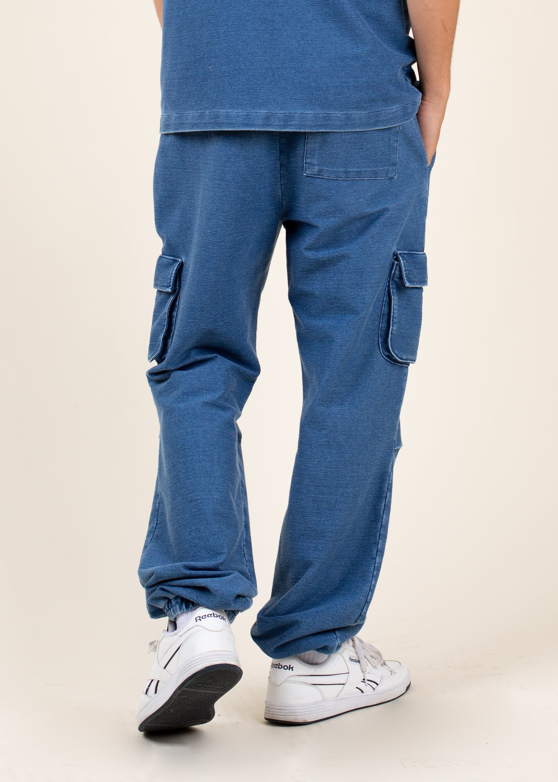 Men's blue cargo pants with patch pockets, styled with white Reebok sneakers