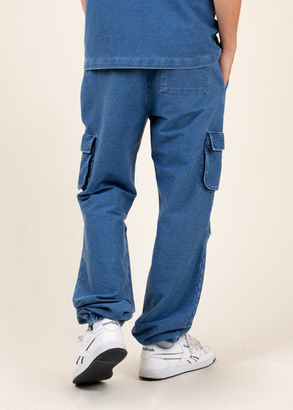 Men's blue cargo pants with patch pockets, styled with white Reebok sneakers