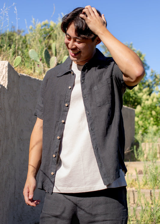 Man in vintage black linen button-down shirt and shorts outdoors, casual men’s fashion
