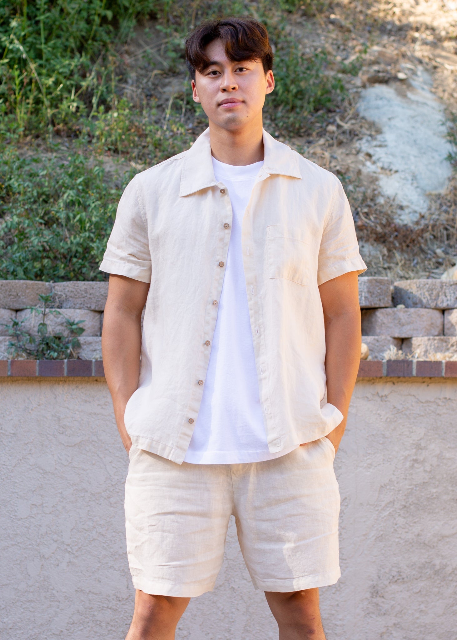 Man wearing coconut milk beige linen short sleeve shirt and shorts set outdoors
