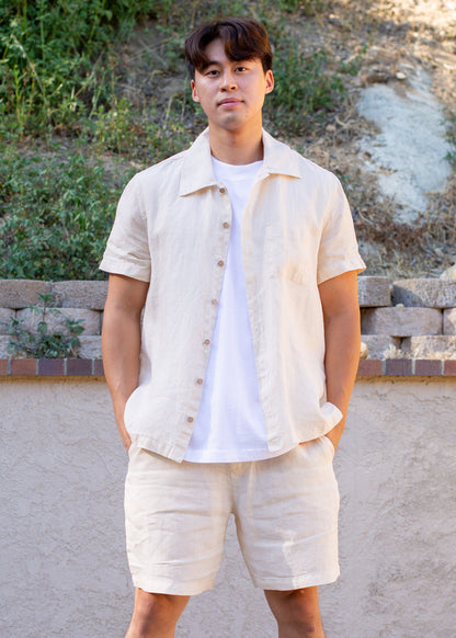 Man wearing coconut milk beige linen short sleeve shirt and shorts set outdoors