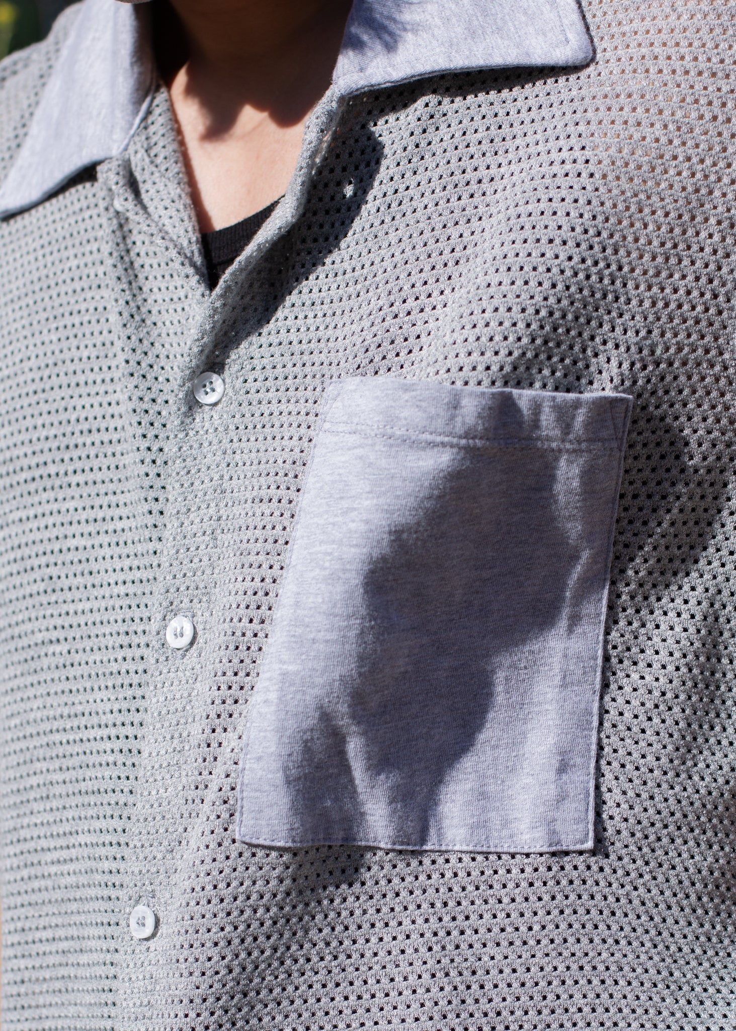Close-up of a men's grey mesh button-down shirt with chest pocket, sunlight detail, MANN fashion