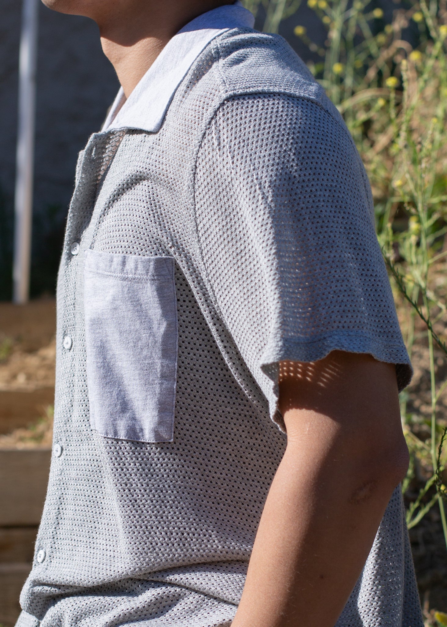 Man wearing a light grey mesh button-down shirt with chest pocket outdoors